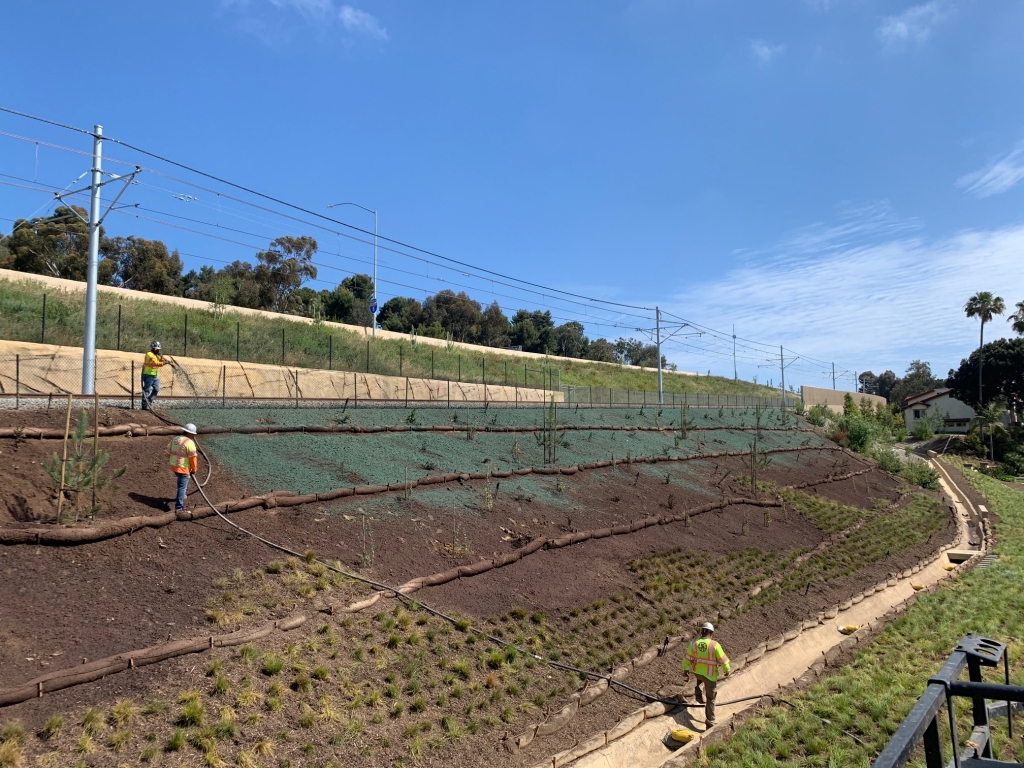 Workers applying the hydraulic erosion control product to the slopes along the railway.